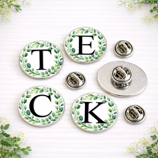 Personalised eucalyptus initial lapel pins in 18mm and 25mm sizes with botanical wreath design for wedding suits