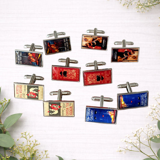 Selection of rectangular book cover cufflinks featuring classic novel designs displayed on a light background.
