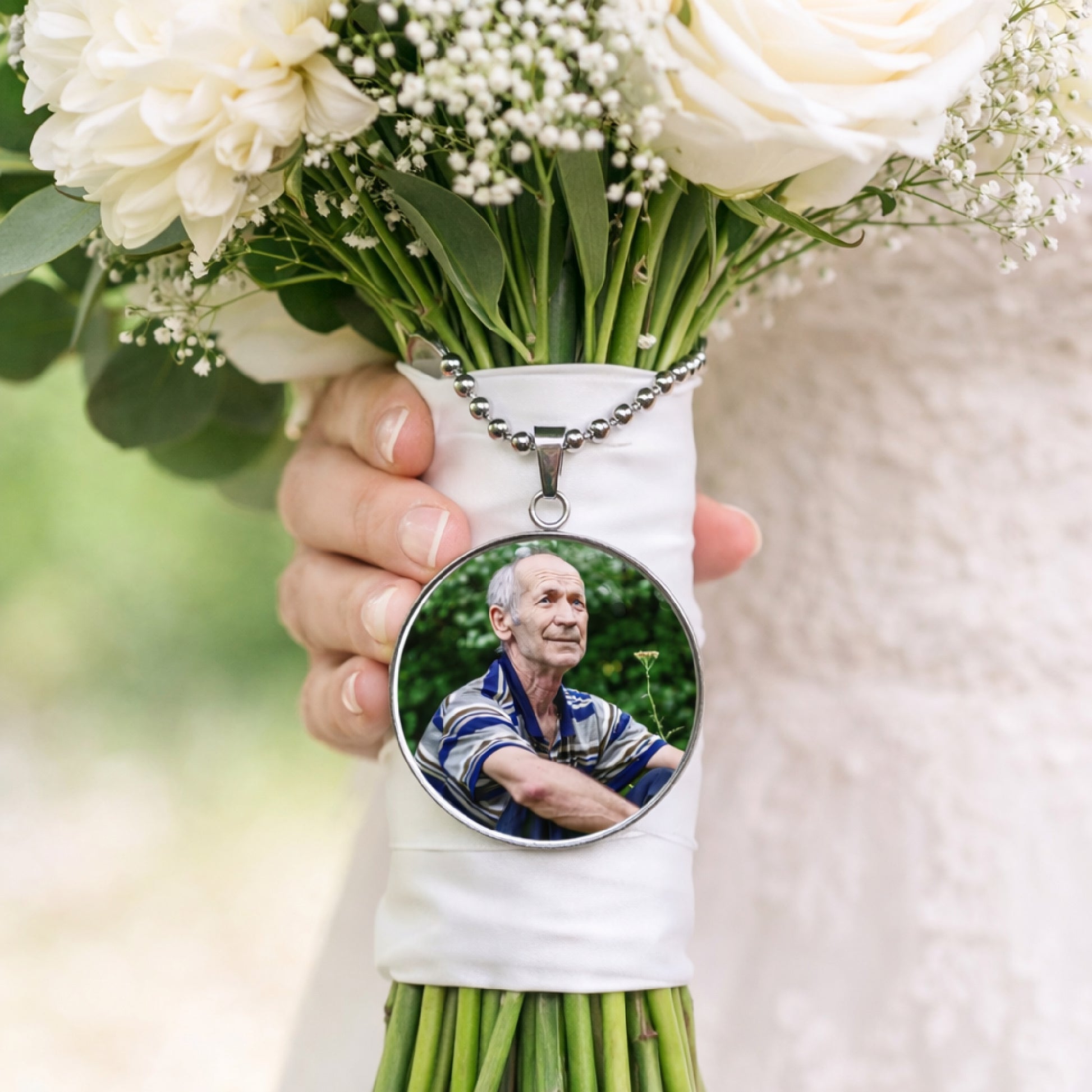 Bridal bouquet with white flowers featuring a personalised memorial photo charm attached to the wrapped stems.