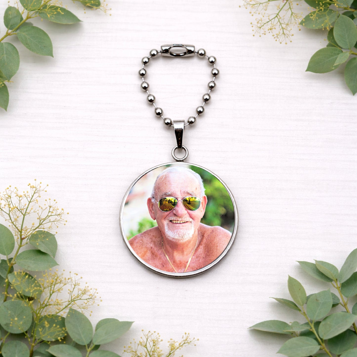 Close-up of personalised wedding bouquet charm featuring an elderly man’s photo set in a 30mm round silver pendant.