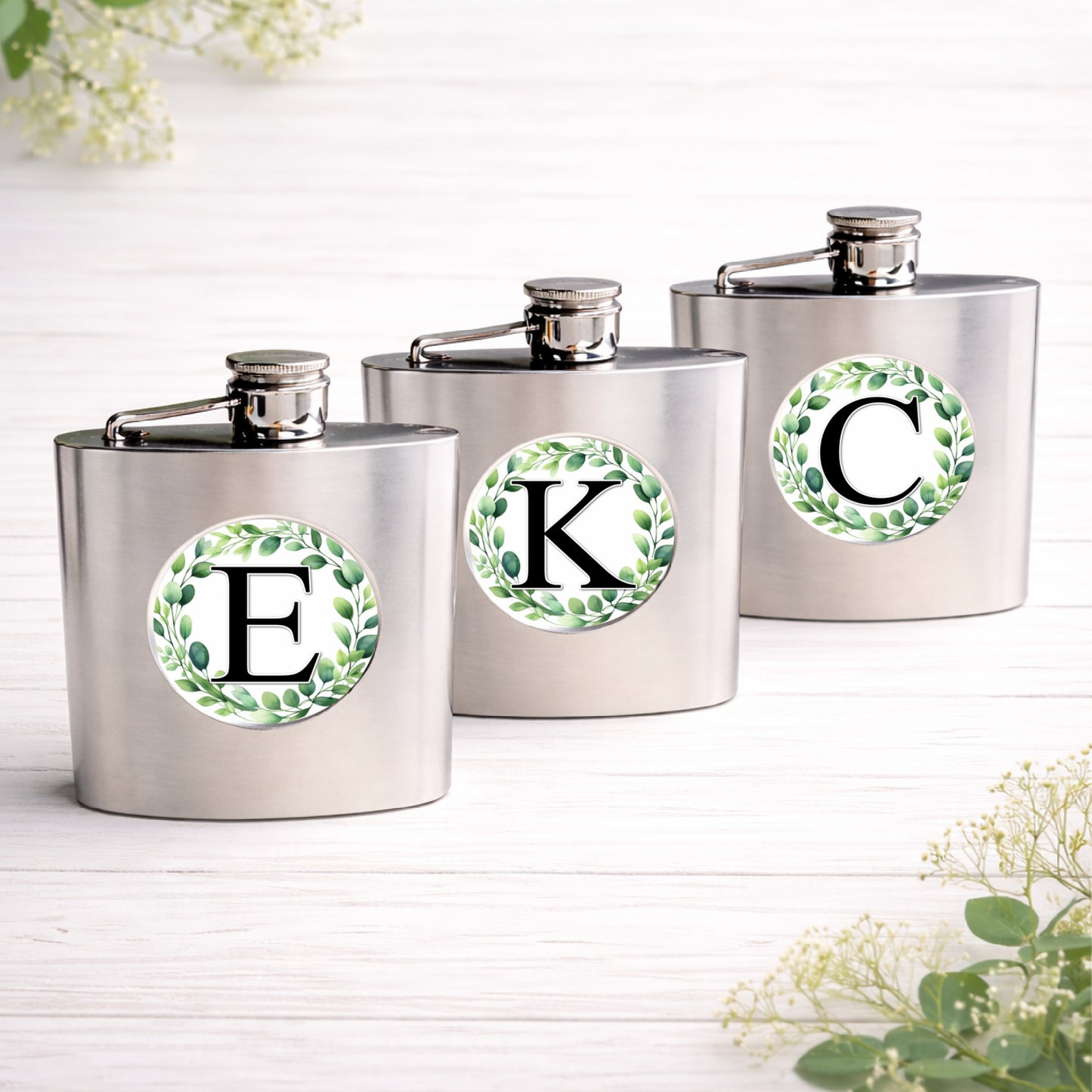 Brushed stainless steel 6oz hip flask personalised with a eucalyptus wreath initial design, custom wedding party gift
