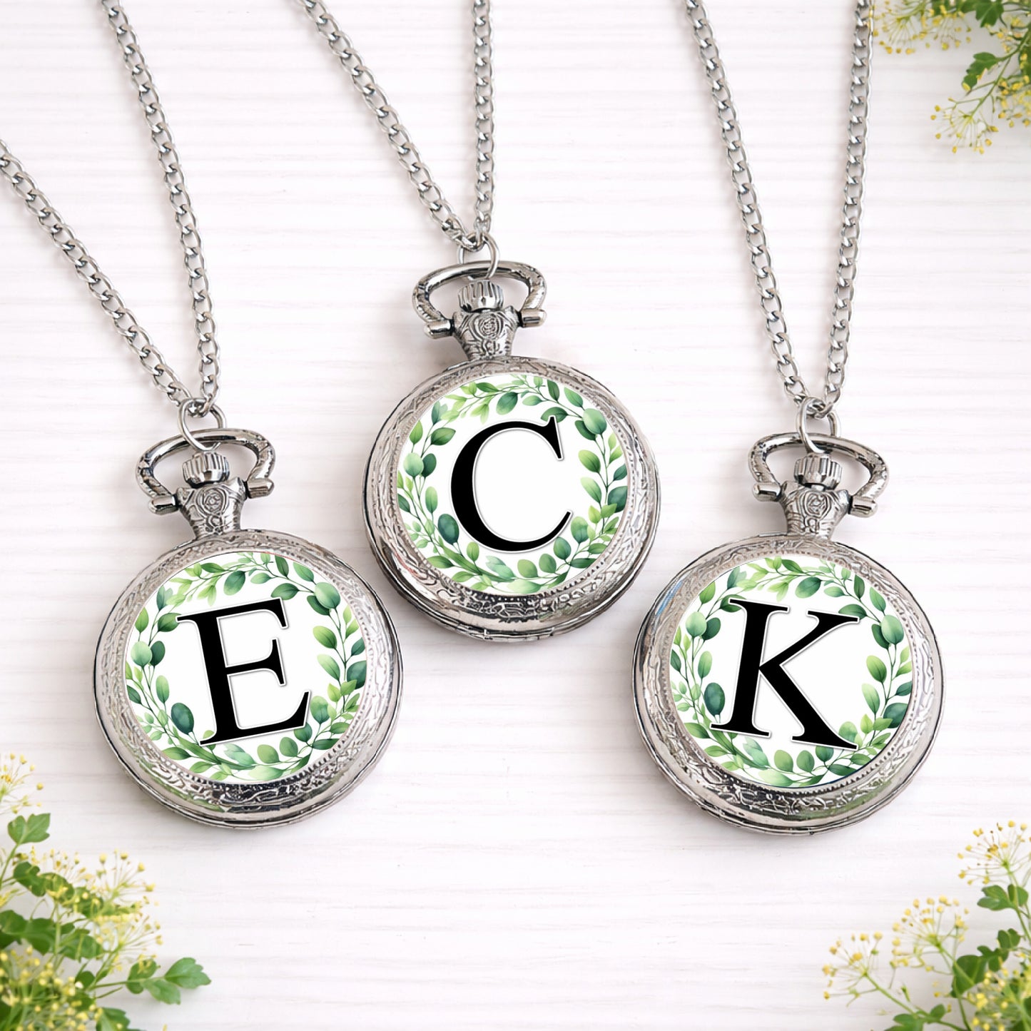 Silver personalised pocket watch with eucalyptus wreath initial design on front, shown open with classic quartz face and necklace style chain.