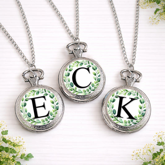 Silver personalised pocket watch with eucalyptus wreath initial design on front, shown open with classic quartz face and necklace style chain.