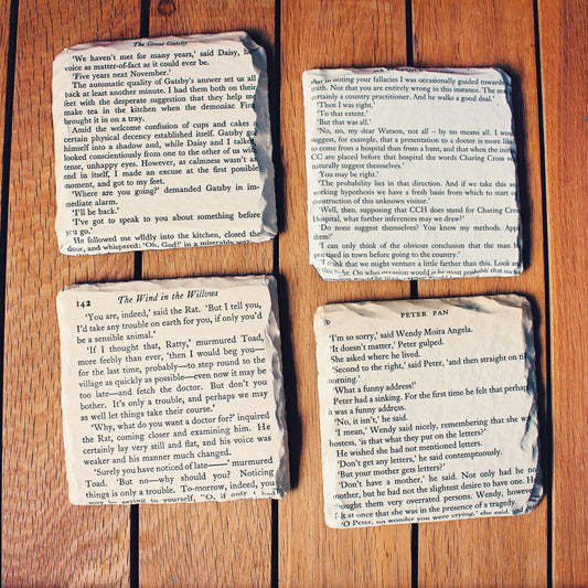 Set of reclaimed vintage book page slate coasters made from classic public domain novels, featuring aged paper mounted onto natural slate bases for a literary wedding theme.