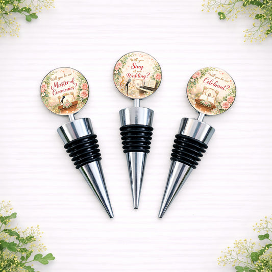 Personalised wedding role proposal bottle stoppers featuring floral designs with wording such as Will you be our Master of Ceremonies, Will you be our Witness and Will you Read at our Wedding, displayed on silver metal wine bottle stoppers.